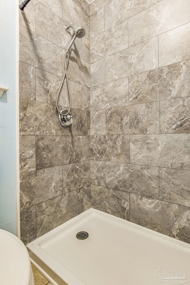 bathroom featuring a tile shower and toilet