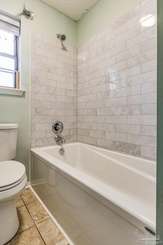 bathroom with tiled shower / bath combo, tile patterned floors, a textured ceiling, and toilet