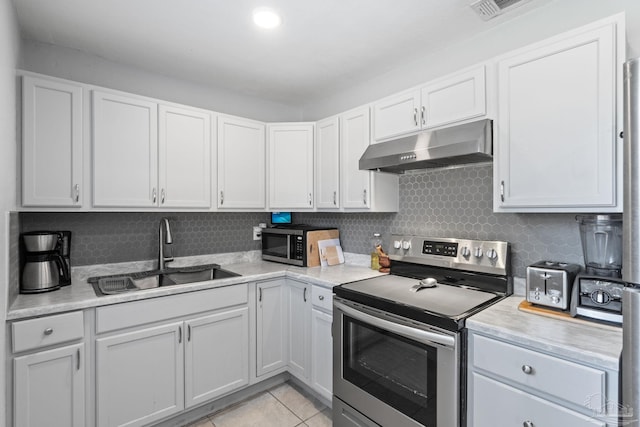 kitchen featuring sink, light tile patterned floors, appliances with stainless steel finishes, tasteful backsplash, and white cabinets