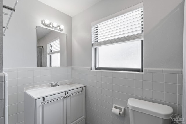 bathroom with vanity, toilet, tile walls, and walk in shower