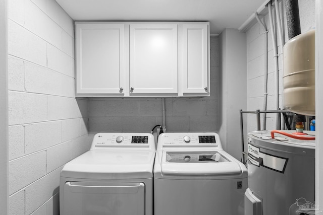 clothes washing area featuring cabinets, washing machine and dryer, and electric water heater