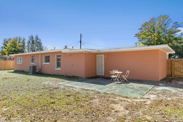 rear view of property with a patio, central AC unit, and a lawn