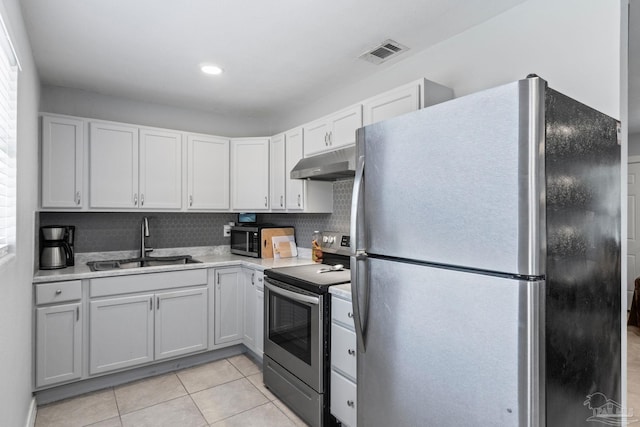 kitchen featuring sink, tasteful backsplash, white cabinetry, light tile patterned floors, and stainless steel appliances