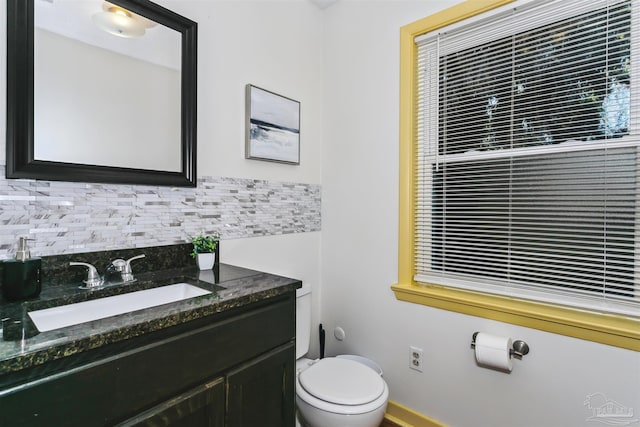 bathroom featuring vanity, toilet, and tasteful backsplash