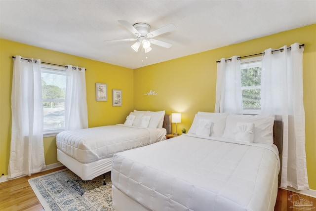 bedroom with ceiling fan, light wood-type flooring, and multiple windows