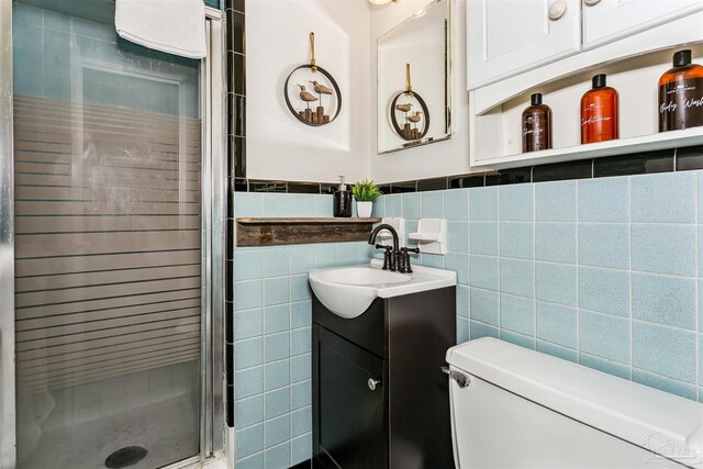 bathroom with a shower with door, vanity, tasteful backsplash, tile walls, and toilet