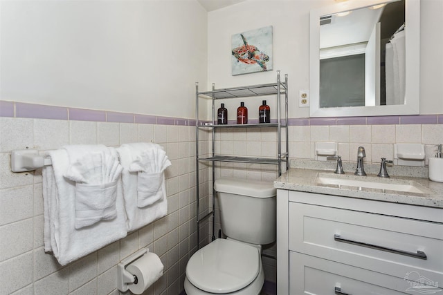 bathroom with tile walls, toilet, vanity, and tasteful backsplash