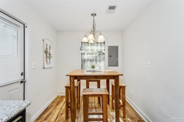 dining area featuring electric panel, light hardwood / wood-style flooring, and an inviting chandelier