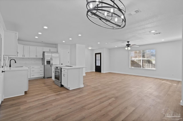 kitchen featuring ceiling fan with notable chandelier, white cabinets, a center island, stainless steel appliances, and sink