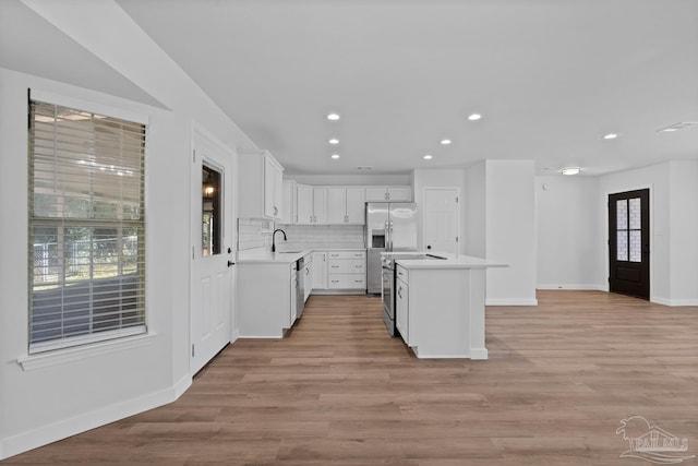 kitchen with tasteful backsplash, a center island, sink, white cabinetry, and appliances with stainless steel finishes