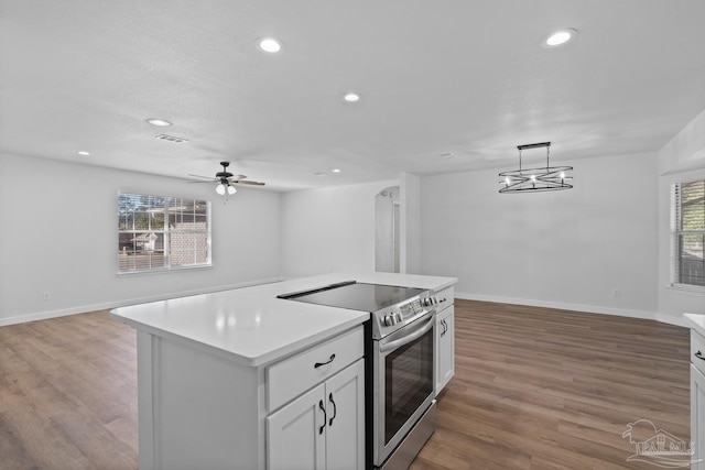 kitchen featuring white cabinetry, stainless steel electric range oven, hardwood / wood-style flooring, hanging light fixtures, and a kitchen island