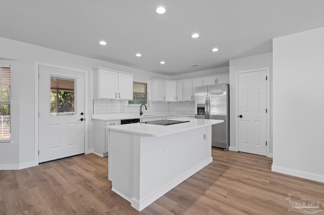 kitchen featuring white cabinets, black appliances, a kitchen island, tasteful backsplash, and light hardwood / wood-style flooring