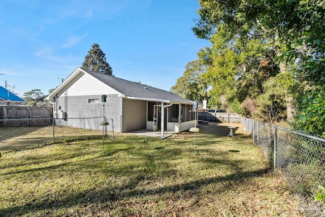 rear view of house featuring a patio, a yard, and a sunroom