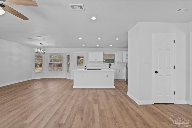 unfurnished living room with sink, ceiling fan with notable chandelier, and light hardwood / wood-style floors