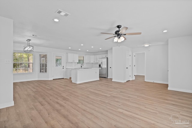 unfurnished living room with sink, ceiling fan with notable chandelier, and light hardwood / wood-style flooring