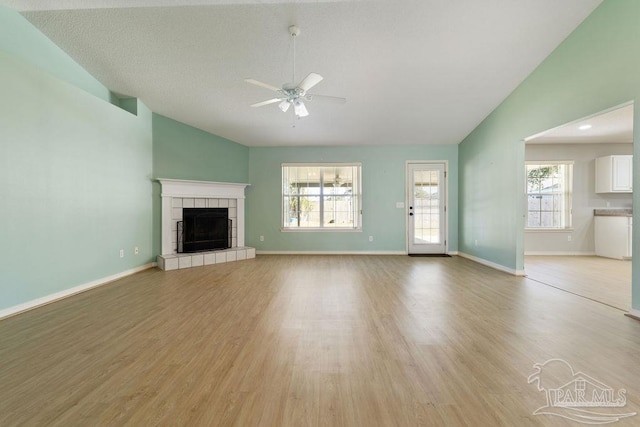 unfurnished living room with a fireplace, baseboards, light wood-style floors, and a ceiling fan