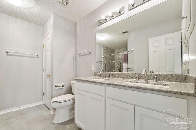 bathroom with a sink, visible vents, tiled shower, and toilet