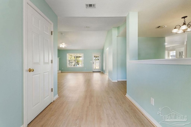 corridor with visible vents, light wood-style floors, baseboards, and a chandelier