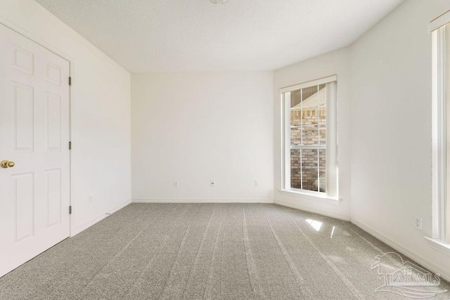 carpeted spare room featuring baseboards and a textured ceiling