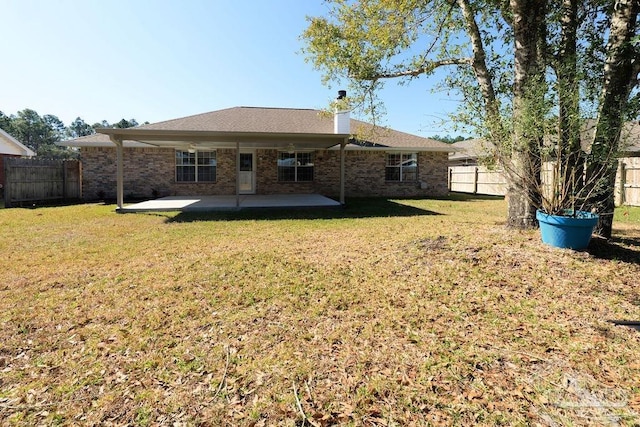 rear view of house with brick siding, a patio area, a lawn, and a fenced backyard