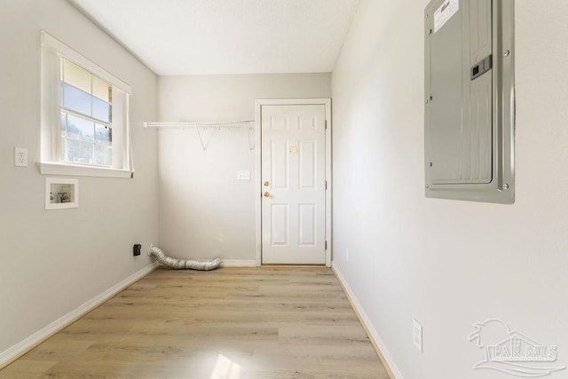 laundry room featuring electric panel, baseboards, light wood-style floors, and laundry area