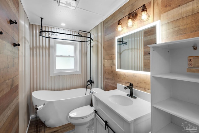 4881 Calvin Dr, Milton, FL 32583 - bathroom featuring a freestanding tub, vanity, wooden walls, wood finished floors, and toilet