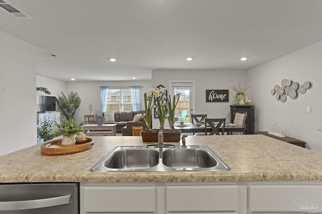 kitchen with light countertops, white cabinets, a sink, and stainless steel dishwasher