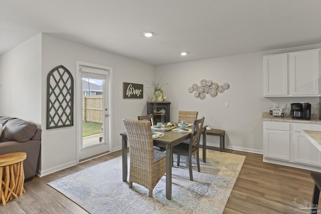 dining space featuring baseboards, wood finished floors, and recessed lighting