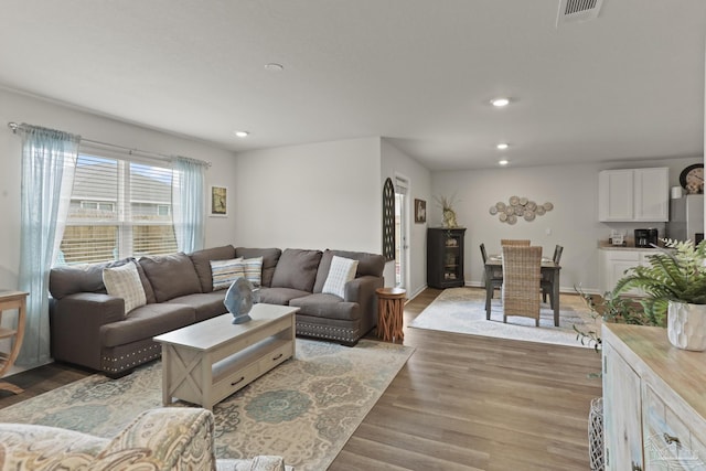 living room featuring baseboards, visible vents, wood finished floors, and recessed lighting