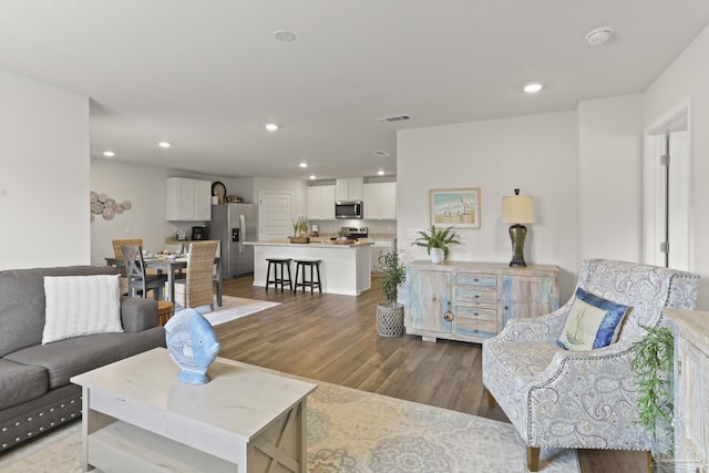 living room with visible vents, wood finished floors, and recessed lighting