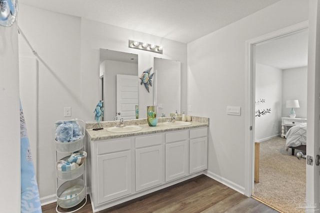 ensuite bathroom featuring baseboards, double vanity, a sink, and connected bathroom