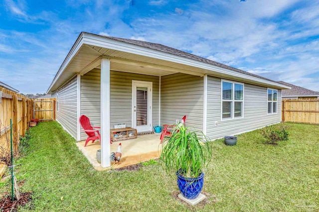 rear view of house featuring a fenced backyard, a patio, and a lawn