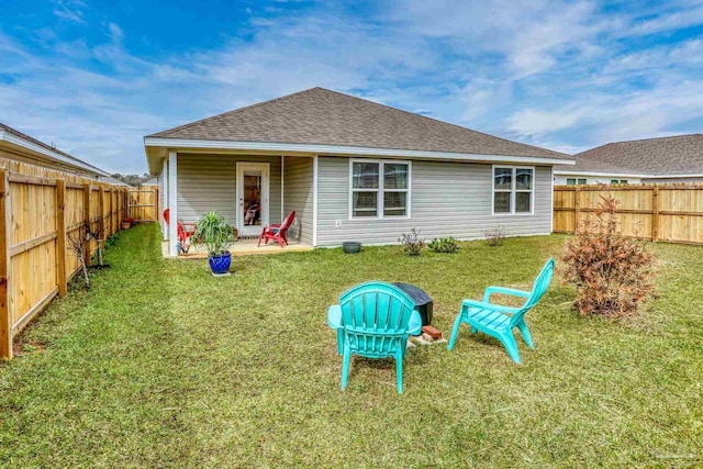 back of property featuring a shingled roof, a lawn, a patio area, and a fenced backyard