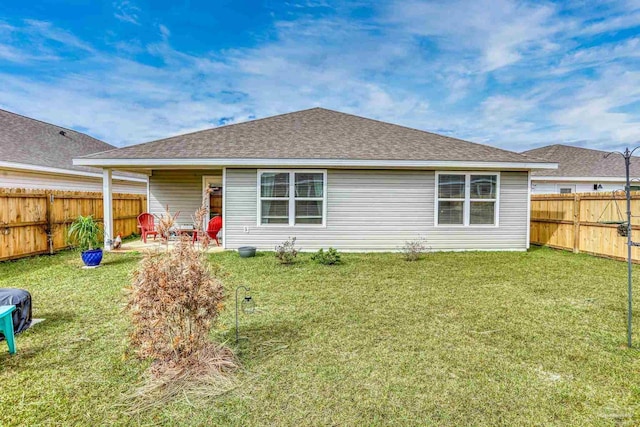 back of property featuring a shingled roof, a fenced backyard, and a lawn