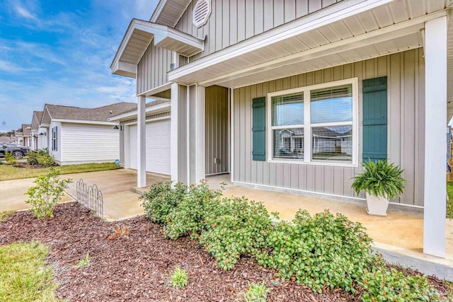 doorway to property with board and batten siding, driveway, and a garage