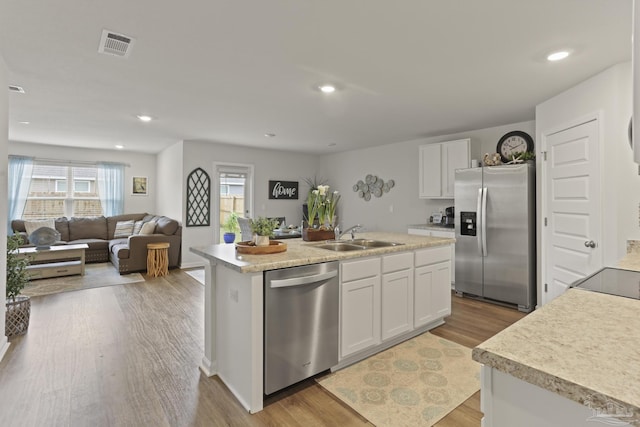 kitchen featuring an island with sink, white cabinetry, stainless steel appliances, and a sink