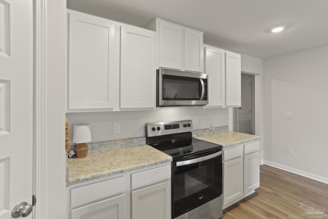 kitchen with appliances with stainless steel finishes, light wood-type flooring, and white cabinetry