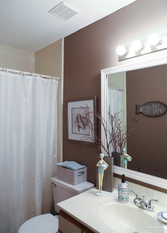 bathroom featuring vanity, toilet, and a textured ceiling