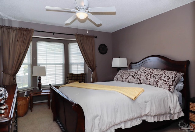 bedroom featuring light carpet, a textured ceiling, and ceiling fan