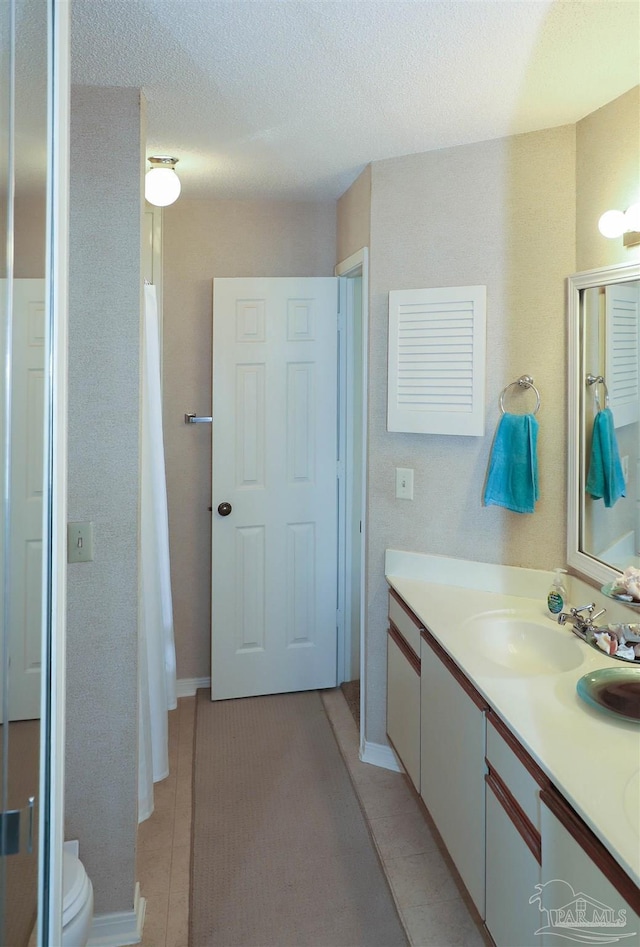 bathroom with vanity, tile patterned floors, a textured ceiling, and toilet