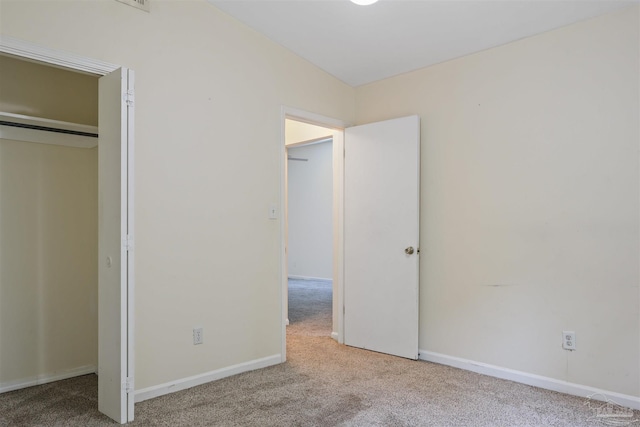 unfurnished bedroom with light colored carpet, a closet, and lofted ceiling