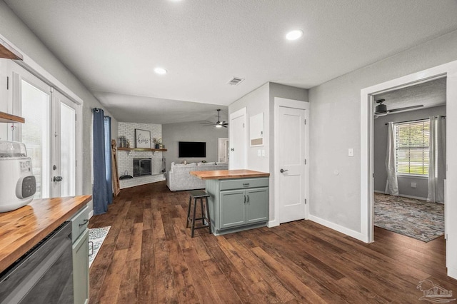 4684 Evelyn St, Pace, FL 32571 - kitchen with butcher block countertops, ceiling fan, a fireplace, a textured ceiling, and dark wood-style flooring