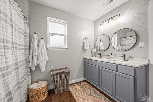 4684 Evelyn St, Pace, FL 32571 - full bath featuring wood finished floors, baseboards, double vanity, a textured wall, and curtained shower