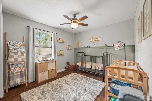 4684 Evelyn St, Pace, FL 32571 - bedroom featuring dark wood-style floors, a crib, ceiling fan, and baseboards