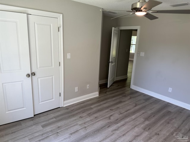 unfurnished bedroom featuring ceiling fan, hardwood / wood-style flooring, and a closet