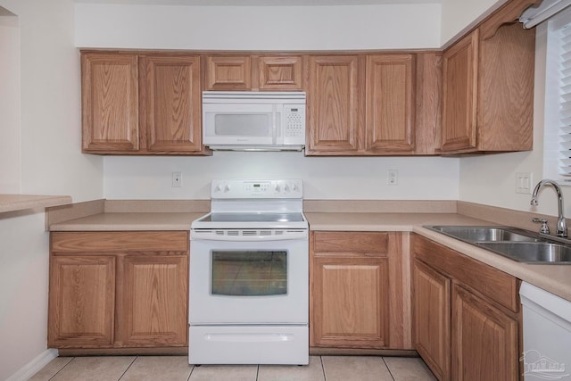 kitchen with white appliances, light tile patterned floors, and sink