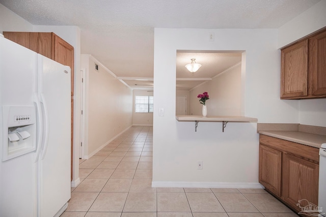 kitchen featuring ornamental molding, a textured ceiling, light tile patterned floors, and white appliances