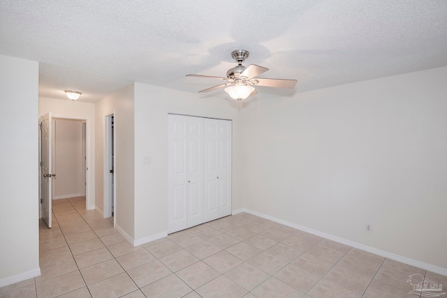 unfurnished bedroom featuring a textured ceiling, light tile patterned floors, ceiling fan, and a closet