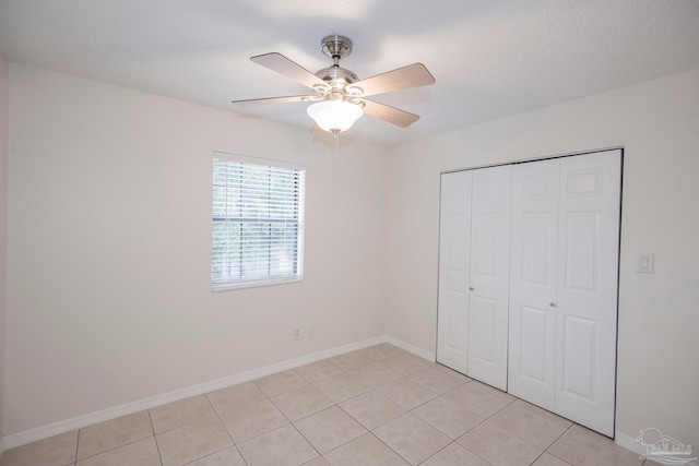 unfurnished bedroom with ceiling fan, a textured ceiling, a closet, and light tile patterned floors