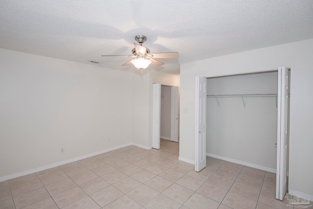 unfurnished bedroom featuring a closet, ceiling fan, light tile patterned floors, and a textured ceiling